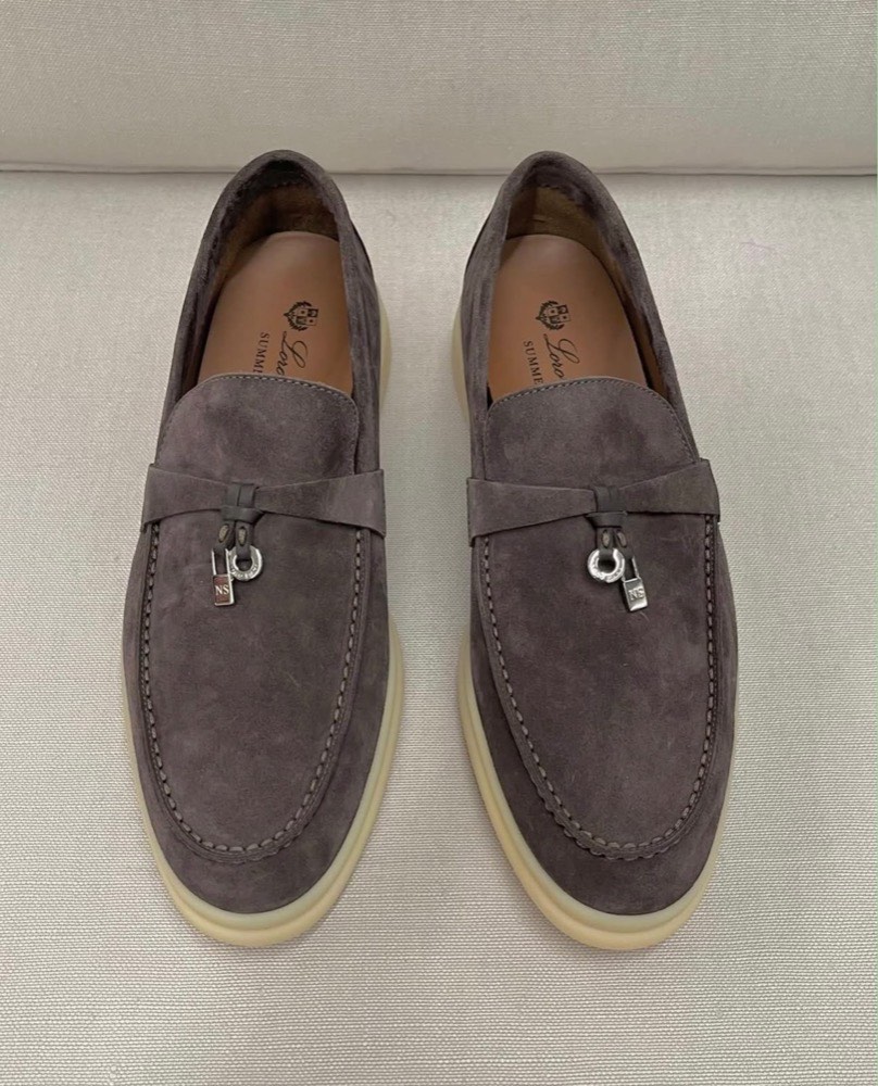 A pair of grey suede loafers with silver charms